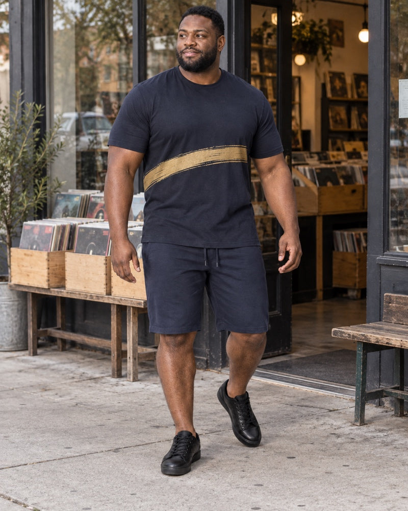 Deep Navy Brass Offset Sweep outfit worn at an ordinary independent record-shop entrance with plain storage crates, a low bench, concrete sidewalk and unbranded window