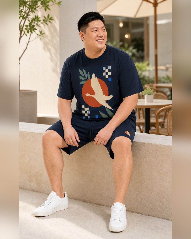 Big and tall man seated and smiling in the Solar Heron Archive T-shirt and shorts set